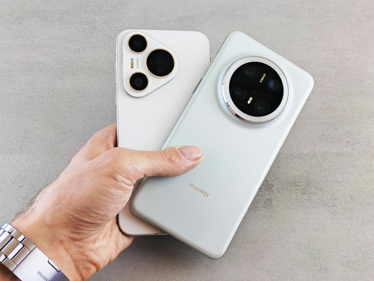 A hand holds two smartphones with prominent camera systems.